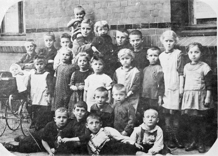 Gruppenfoto mit über 20 Kindern vor Ziegelwand, einige schauen ernst