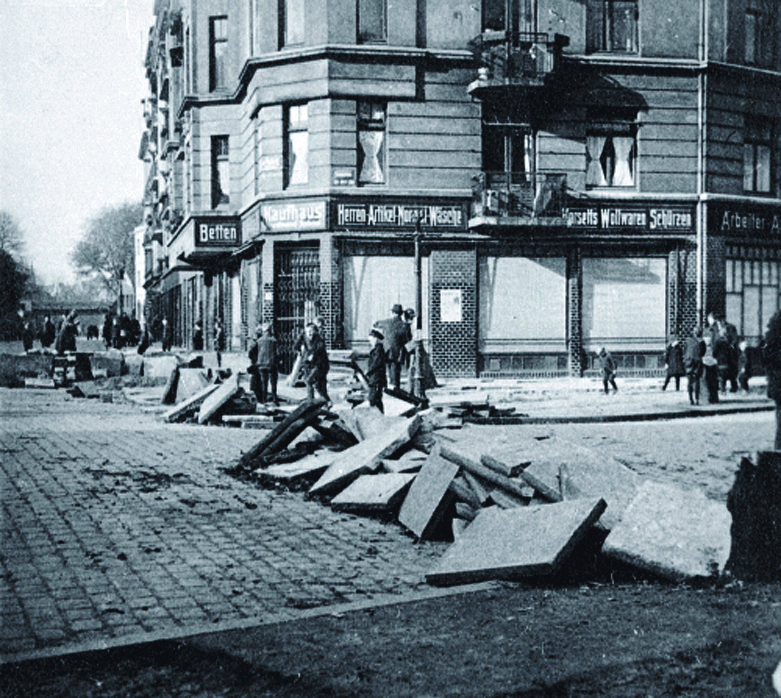 Altes Foto mit Barrikaden auf Straße vor einem Kaufhaus, Menschen stehen drumherum