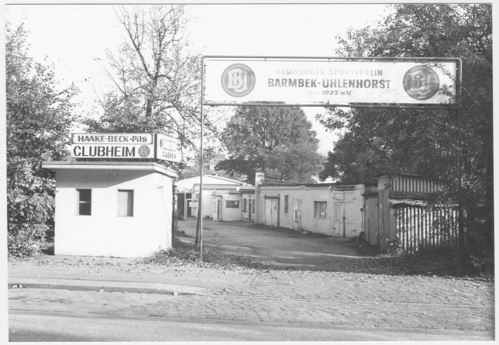 Eingang zum Clubheim des HSV Barmbek-Uhlenhorst mit Schild und flachen Gebäuden